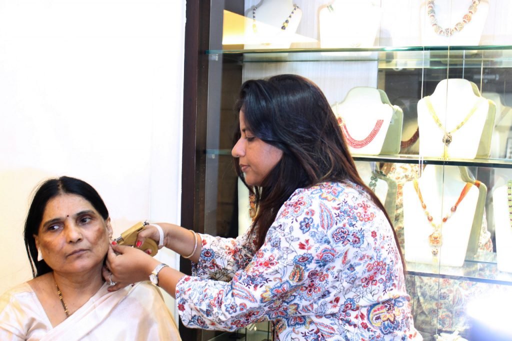 A woman assists an older woman in putting on earrings in Mumbai, showcasing a moment of care and connection.jpg