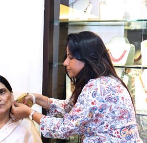 A woman assists an older woman in putting on earrings in Mumbai, showcasing a moment of care and connection.jpg